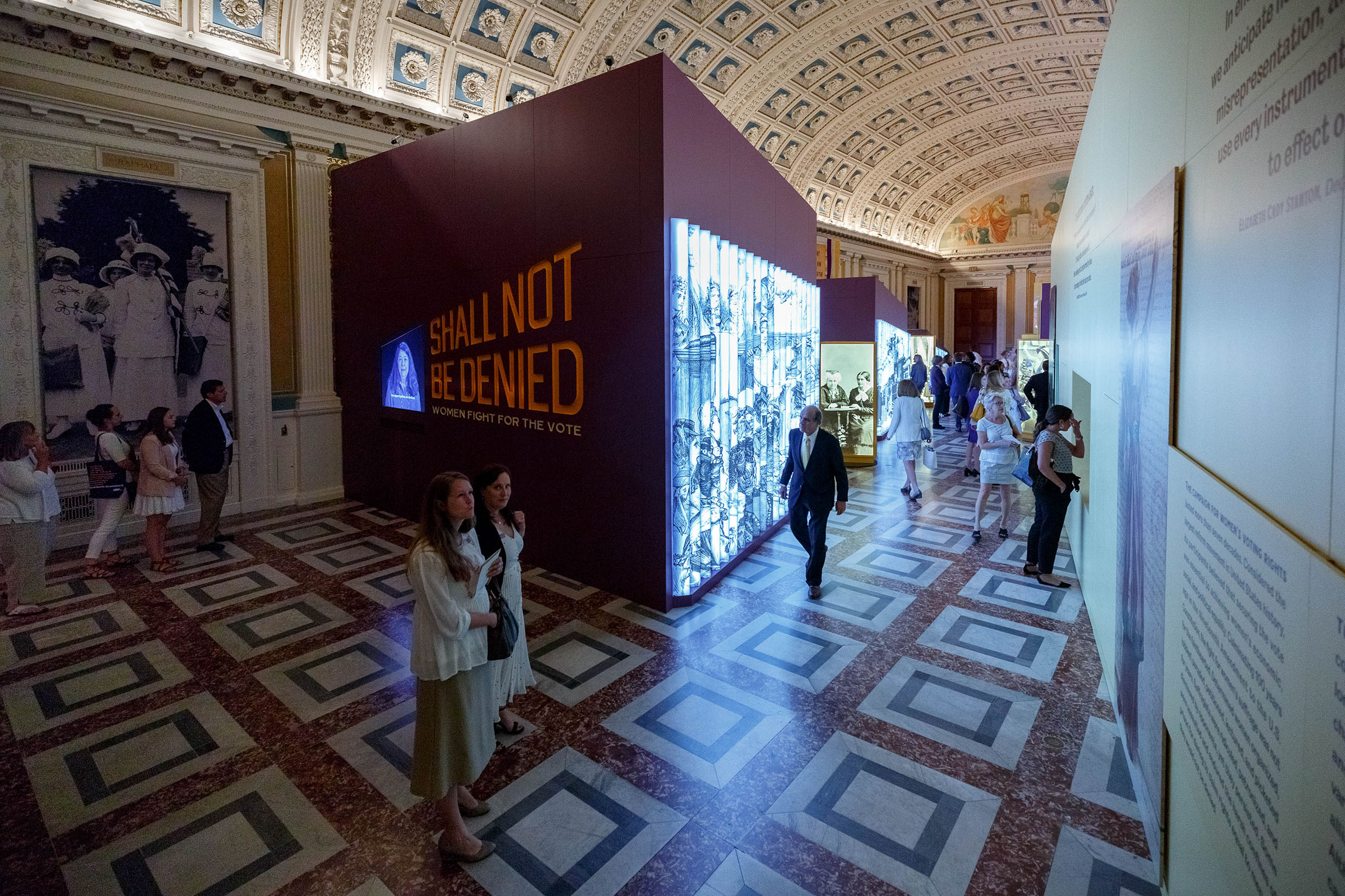 Shall Not Be Denied Exhibition Opening: The “street” is comprised of large, backlit, lenticular images of suffragists protesting—first in private spaces, and then in public—across the 160+ years of the struggle for the vote and the fight for women’s rights.